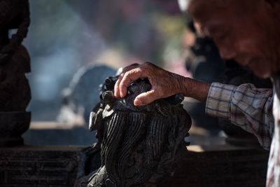 Cropped hand of man on sculpture outdoors