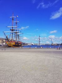 Sailboats on pier at harbor against blue sky