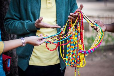 Midsection of vendor selling bead necklace to customers