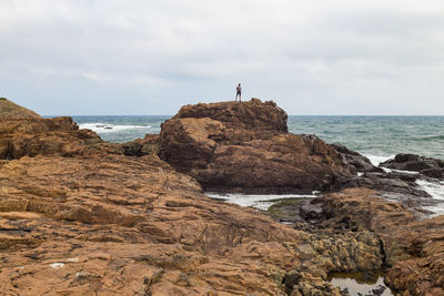 Rock formations on beach against sky