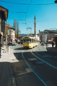 Cars on city street by buildings against sky