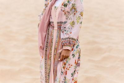 Midsection of woman in traditional clothing standing on sand at beach