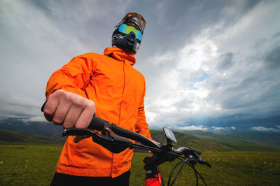 Rider in a full face helmet and protective gear on a mtb bike stands in a field against the backdrop