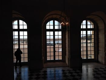 Silhouette of man standing by window in building
