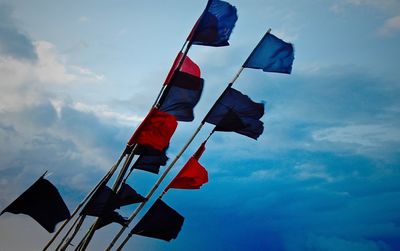 Low angle view of red and blue flags against sky