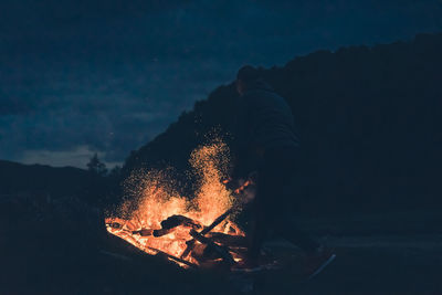 Man burning bonfire at night