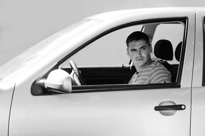 Serious stylish caucasian young man sitting in car. 20s guy driver. silver gray car. attractive