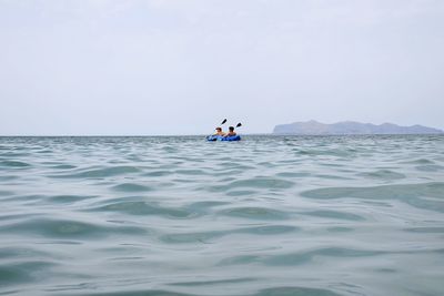 People on boat in sea against sky