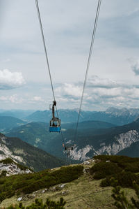 Overhead cable car over mountains against sky