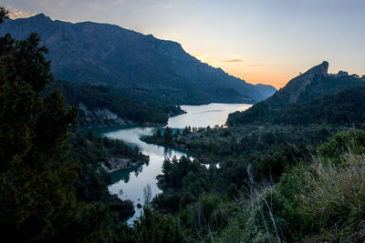 Scenic view of lake and mountains against sky at sunset