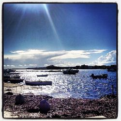 Boats in sea against cloudy sky