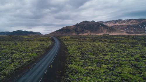 Road leading towards mountains against sky