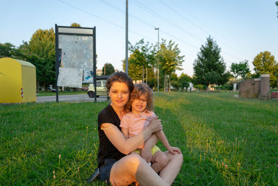 Portrait of mother with daughter sitting on grassy field