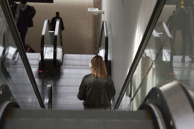 Rear view of woman sitting on escalator
