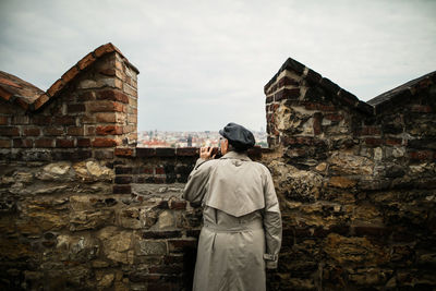 Rear view of man standing against built structure