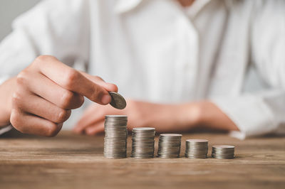 Midsection of man stacking coins on table