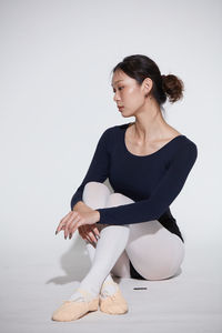 Young woman exercising against white background