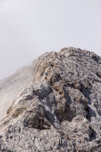 Distant view of people climbing mountain during winter