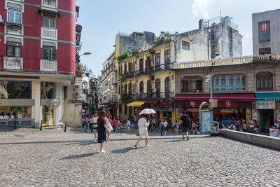 People walking on street against buildings in city