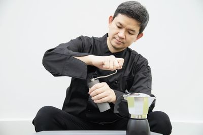 Asian barista is grinding coffee bean prepare to make coffee using moka pot