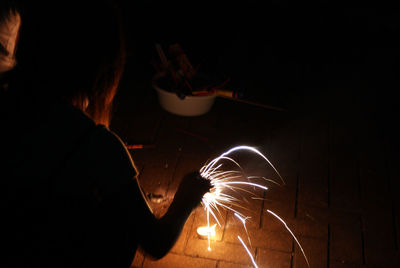 Man holding illuminated fire in dark room