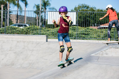 Teen girl skateboards at a skatepark while scratching her face