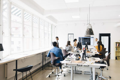 Computer programmers discussing over code during meeting in creative office