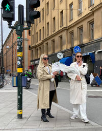 Portrait of friends standing on footpath in city