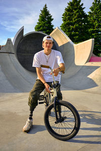 Portrait of bmx rider with prosthetic foot confidently posing on bike at skateboard park