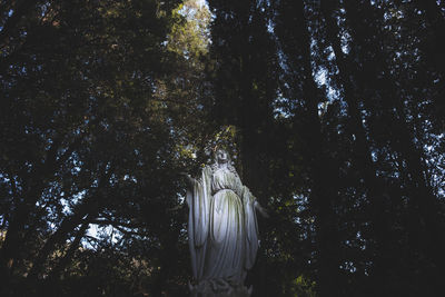Low angle view of statue against trees in forest