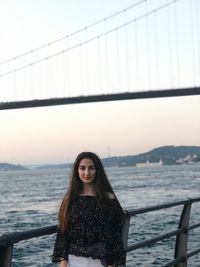 Portrait of beautiful woman by railing against sea