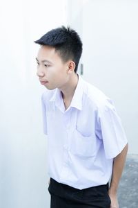 Young man looking away against wall