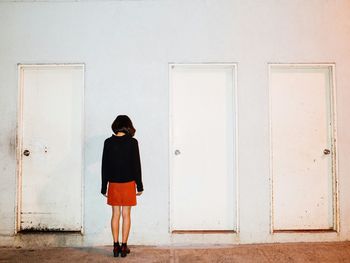 Rear view of woman standing against wall