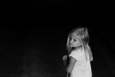 Cute girl looking away while standing on floor at night