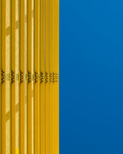 Close-up of yellow metal against blue sky