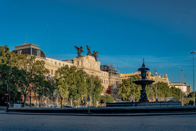 Statue in city against clear blue sky