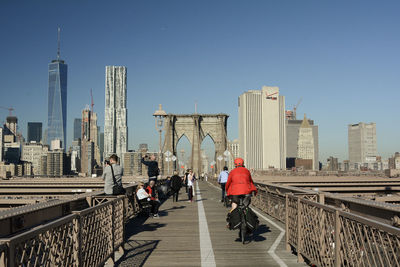 People at brooklyn bridge in manhattan against clear sky