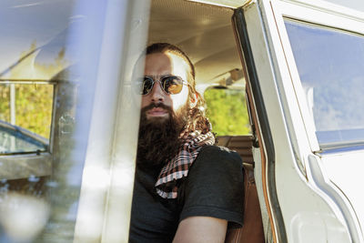 Bearded man sitting in a parked vintage car