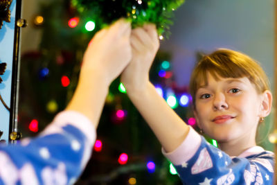 Little blonde caucasian girl 10 years old in pajamas decorate home for christmas. portrait
