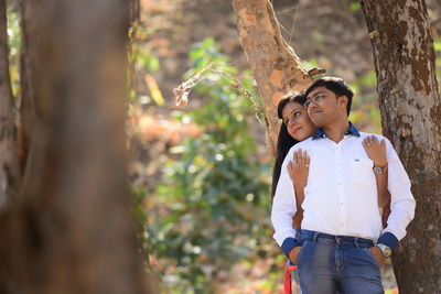 Young couple standing on tree trunk in forest