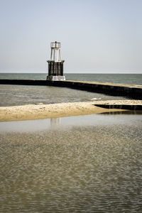 Lighthouse on beach against clear sky