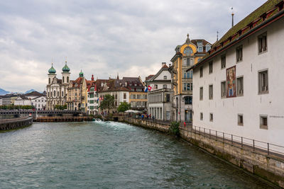 Buildings by river against sky