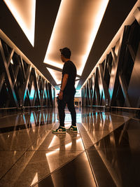 Rear view of man walking on illuminated bridge