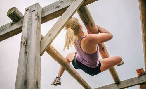 Low angle view of woman climbing on wood