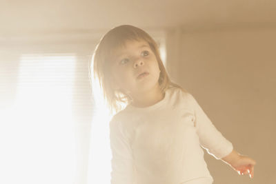 Portrait of cute girl standing against wall