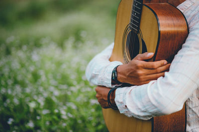 Midsection of man holding guitar in park