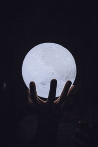 Close-up of hand holding moon against sky at night