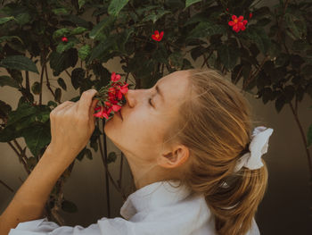 Portrait of girl smelling  red flowers