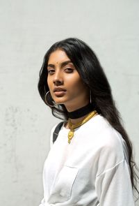 Portrait of beautiful young woman standing against white wall