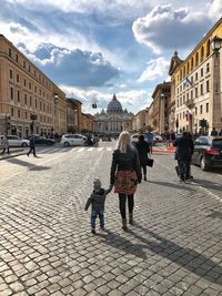 Rear view of people walking on street in city